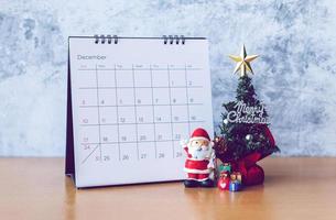 calendrier de décembre et décoration de noël - père noël, arbre et cadeau sur table en bois. concept de noël et bonne année photo