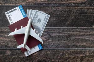 avion jouet, billet d'avion, cartes de crédit, dollars et passeport sur table en bois. notion de voyage photo