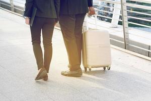 homme d'affaires et femme d'affaires tirant une valise dans une grande ville. photo