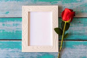 cadre photo vierge et roses rouges sur table en bois