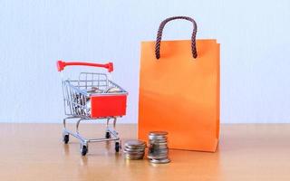 chariot supermarché et sac en papier orange sur table en bois. notion de magasinage photo