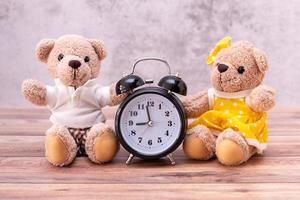 couple ours en peluche et horloge sur table en bois. célébration de la saint valentin photo