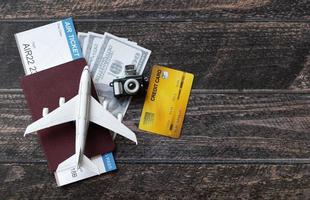 avion jouet, billet d'avion, cartes de crédit, dollars et passeport sur table en bois. notion de voyage photo