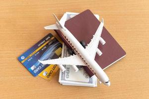 avion jouet, cartes de crédit, dollars et passeport sur table en bois. notion de voyage photo