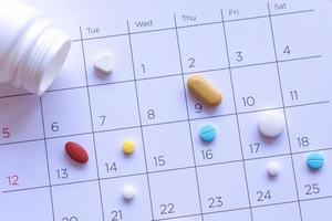 tas de pilules différentes sur un fond de calendrier. concept soins de santé photo