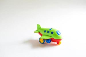 jouet avion en plastique vert avec des détails de couleur rouge, bleu, jaune sur fond blanc. jouet pour enfant, concept de tourisme et de voyage, transport aérien. espace pour le texte photo