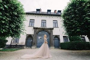 jeune belle femme blonde en robe longue bleue magnifique marchant dans la rue près de l'ancien bâtiment de la vieille ville. photo