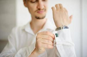 un homme redresse les boutons de manchette sur une chemise. fermer. photo