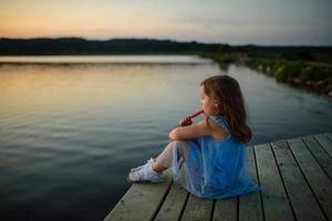 une petite fille tient un dessert dans ses mains et veut beaucoup le manger. photo