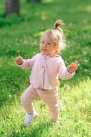 petite fille en vêtements décontractés fait ses premiers pas sur l'herbe. photo