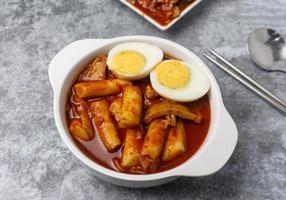 vue de dessus tteokbokki gâteaux de riz épicés avec des œufs durs sur la table en béton gris, cuisine de rue coréenne. photo