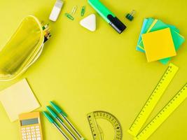 vue de dessus du bureau de bureau vert vif moderne avec des fournitures scolaires sur la table, espace vide pour le texte. concept de retour à l'école. photo