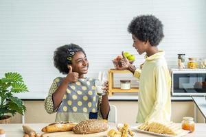 deux mignons adorables frères et sœurs enfants afro-américains prenant leur petit déjeuner avec du lait à la cuisine, portrait d'un frère heureux buvant du lait avec sa sœur et le pouce levé, concept de nourriture et de boisson photo