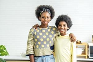 enfants heureux.deux frères et sœurs adorables mignons enfants afro-américains étreignent le cou et sourient, la sœur aînée étreint le petit frère par le cou photo