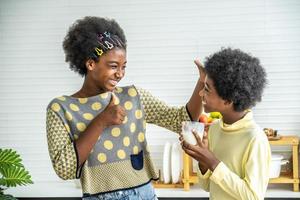 deux mignons adorables frères et sœurs enfants afro-américains prenant leur petit déjeuner avec du lait à la cuisine, portrait d'un frère heureux buvant du lait avec sa sœur et le pouce levé, concept de nourriture et de boisson photo