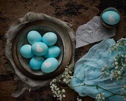 pâques inhabituelles sur fond sombre et ancien. bol marron en céramique avec des oeufs bleus avec lapin. photo