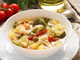 soupe de légumes minestrone avec tomate, céleri, carotte, courgette, brocoli. vue latérale, table en bois rustique grise, gros plan photo