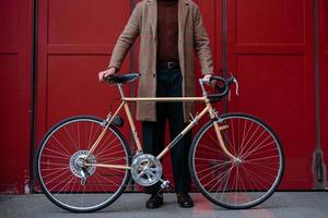 jeune homme d'affaires avec vélo sur fond de mur rouge dans une ville. fond de couleur rouge photo