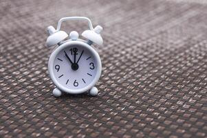 réveil blanc sur chaise de piscine. l'horloge réglée à 11 heures. photo