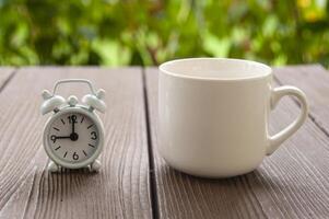 réveil pointant à 9 heures avec tasse à café. arrière-plan flou du parc. concept d'espace de copie photo