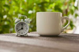 réveil pointant à 8 heures avec une tasse de café sur un banc. concept d'espace de copie photo