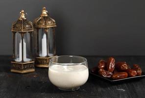 notion de ramadan. lait de dattes susu kurma avec fruit de datte en arrière-plan. lanterne de ramadan sur table en bois. photo