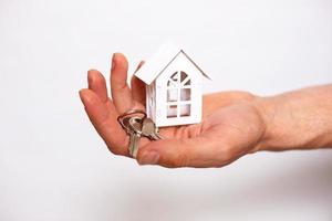 porte-clés avec les clés de la maison sur la main d'un homme sur un fond blanc. agent immobilier, vente de maison neuve, hypothèque, déménagement, banque, réparation et construction photo