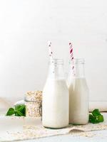 smoothie aux flocons d'avoine, menthe pour un petit-déjeuner sain. lait d'avoine en bouteille de verre avec tube sur fond blanc. photo