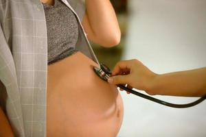 portrait en coupe médiane d'une femme méconnaissable au cours des derniers mois de la grossesse tenant doucement son gros ventre photo