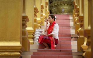 jeune fille asiatique en costume traditionnel birman tenant un bol de riz à portée de main à la pagode d'or du temple du myanmar. myanmar femmes tenant des fleurs avec une robe traditionnelle birmane visitant un temple bouddhiste photo