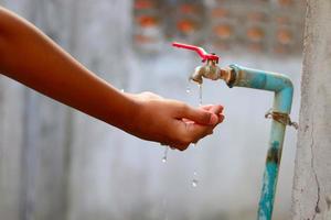 jeunes mains recueillant l'eau d'un vieux robinet photo