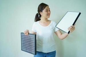 jeune femme asiatique montrant un purificateur d'air usagé et le nouveau filtre à air, comparant entre le filtre à air sale et le nouveau filtre à air usagé. photo