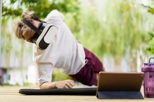 sportif actif faisant un exercice de planche et passant un appel vidéo avec un ami et un entraîneur d'entraînement sportif en ligne en ligne. homme de sport en bonne santé faisant une séance d'entraînement de musculation avec un instructeur en ligne. photo