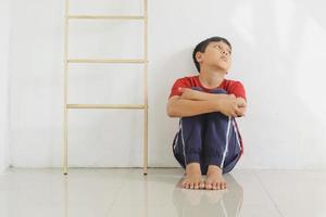 enfant triste et solitaire assis sur le sol contre le mur. expérience traumatique de l'enfance, psychologie, psychologique, syndrome d'Asperger, trouble d'Asperger, autiste, autisme. photo