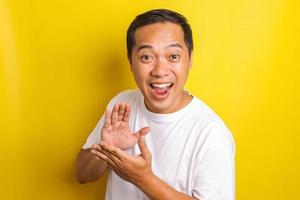 portrait en gros plan d'un homme asiatique joyeux frappant dans ses mains pour donner un soutien isolé sur fond jaune photo