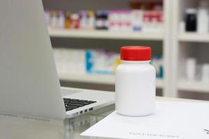 flacon de médicament et ordinateur portable dans la pharmacie photo