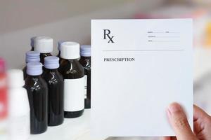 Main tenir le papier d'ordonnance sur les flacons de médicaments photo