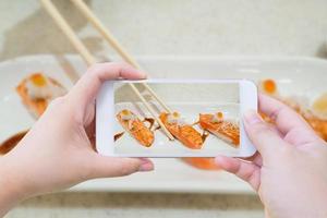prendre des photos de sushis au saumon dans des baguettes
