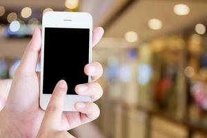 main tenant un téléphone à écran tactile moderne et image floue du centre commercial avec bokeh photo