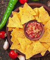 Croustilles de nacho mexicaines et trempette de salsa dans un bol sur fond de bois photo