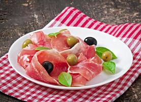 jambon, olives, basilic sur fond de bois ancien photo