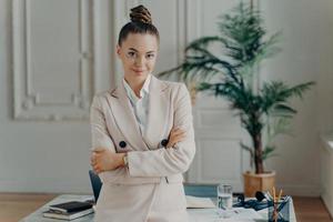 femme d'affaires heureuse en tenue classique posant dans un bureau moderne et léger photo