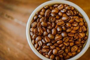 grains de café en tasse sur fond de bois grunge photo