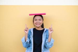 heureuse étudiante jeune fille avec un livre rose sur fond marron. photo