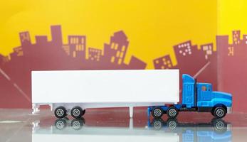jouet de camion conteneur bleu avec vue latérale de remorque conteneur maquette sur fond de ville flou photo