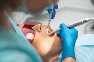 une jeune femme dentiste est en train de travailler avec un patient à bouche ouverte. photo