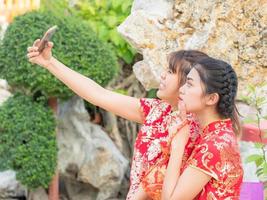 belle fille asiatique habillée en costume national chinois prend des photos avec l'appareil photo du smartphone