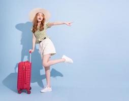 image pleine longueur de jeune fille asiatique avec valise sur fond bleu, concept de voyage photo