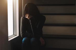 femme assise dépression debout près de la fenêtre et anxiété photo