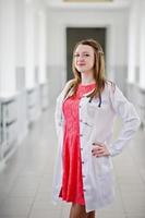 portrait d'un jeune médecin séduisant en blouse blanche avec stéthoscope posant à l'hôpital. photo